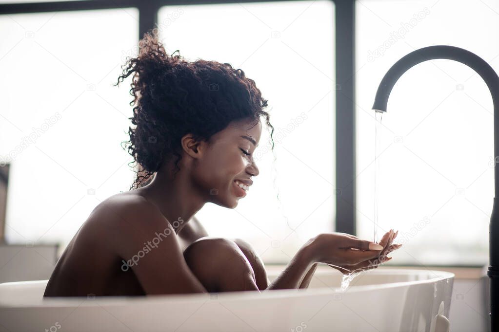 Happy curly woman feeling simply amazing while enjoying water
