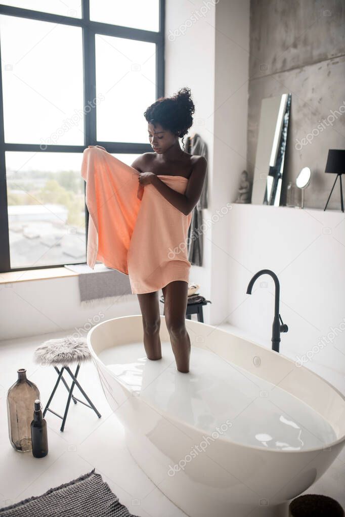Slim appealing woman taking towel after chilling in bath