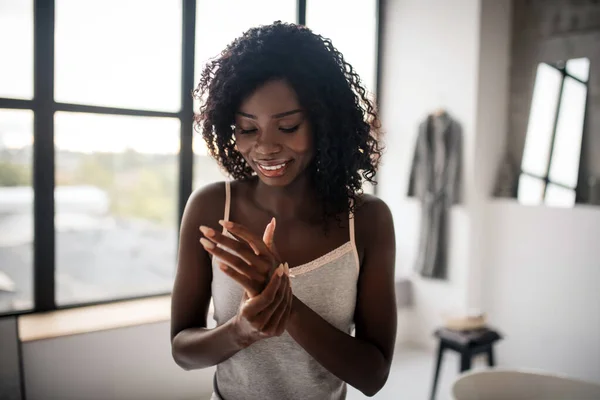 Mujer sonriendo mientras usa crema nutritiva para sus manos —  Fotos de Stock