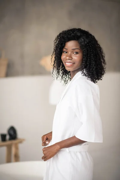 Dark-eyed woman wearing white bathrobe standing in the bathrobe — Stock Photo, Image