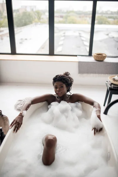 Ovanifrån av lockigt tilltalande kvinna som ligger i badkar med skum — Stockfoto