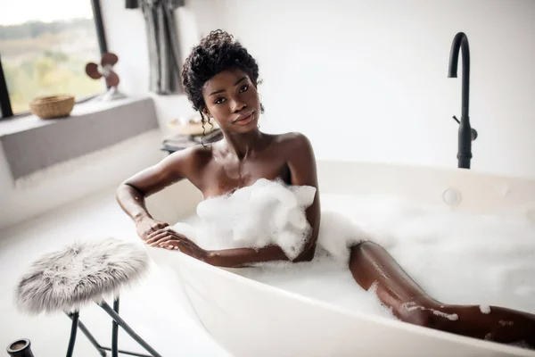 Belle femme aux yeux foncés allongée dans un bain avec de la mousse — Photo