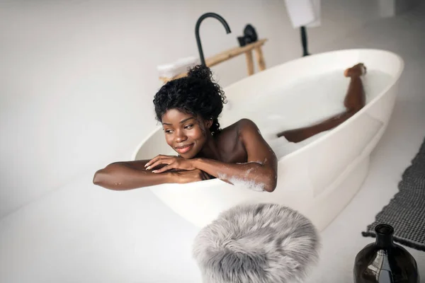 Lockige Frau beginnt ihren Morgen direkt beim Chillen in der Badewanne — Stockfoto