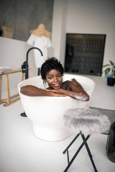 Strålande mörkhyade kvinna som vilar i badkaret i helgen — Stockfoto