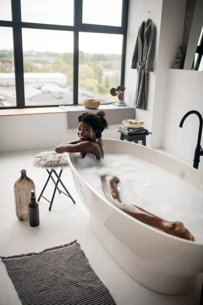 Tmavá žena chladí ve vaně během lázeňského dne — Stock fotografie