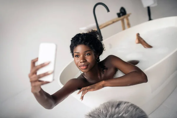 Dunkeläugige Frau macht Selfie beim Schaumbad — Stockfoto