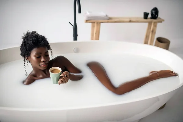 Donna riccia che si rilassa nel bagno e beve caffè con latte — Foto Stock