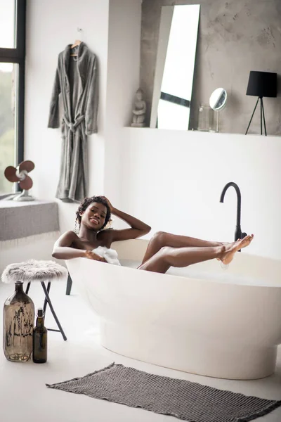 Frau chillt in Badewanne im geräumigen Badezimmer mit modernem Interieur — Stockfoto