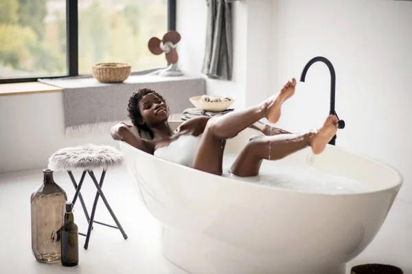 Femme souriante couchée dans le bain avec de la mousse et se sentant excitée — Photo