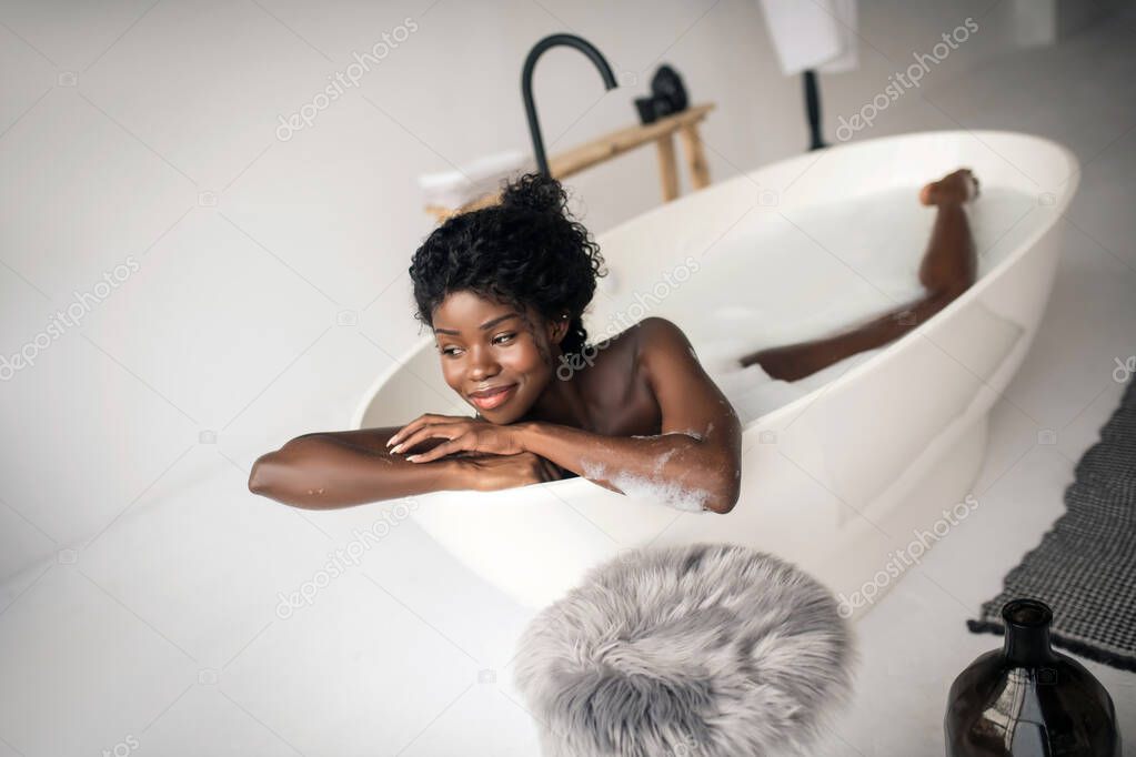 Curly woman starting her morning right while chilling in bath
