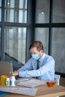 Ofiste çalışırken maske takan bir memur.