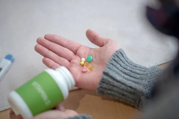 Man wearing grey sweater having pills on palm — Stock Photo, Image