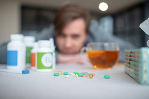 Close up of pills lying on the table near cup of tea