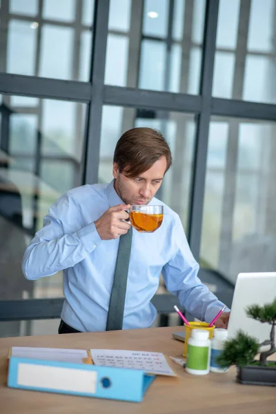 Темноволосый бизнесмен пьет чай в офисе — стоковое фото
