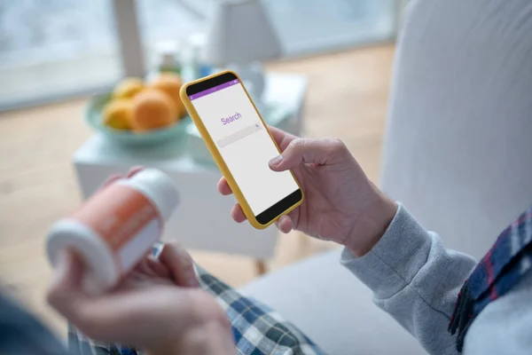 Hombre sosteniendo teléfono inteligente y la búsqueda de vitaminas en Internet —  Fotos de Stock