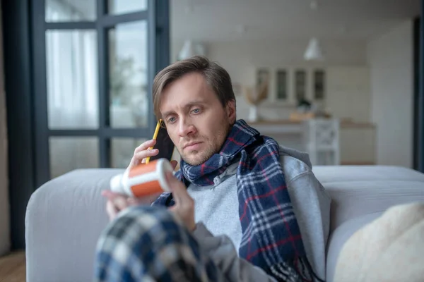 Sick blue-eyed man calling his doctor while having high fever