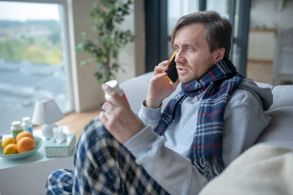 Hombre con bufanda hablando con el médico por teléfono — Foto de Stock