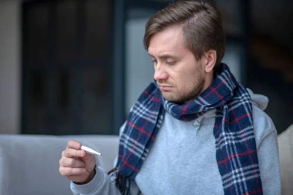 Dark-haired man feeling upset after measuring temperature