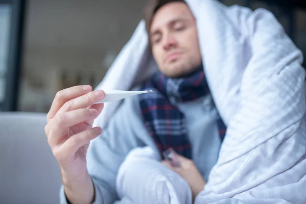 Primer plano del hombre sintiendo frío midiendo la temperatura corporal — Foto de Stock