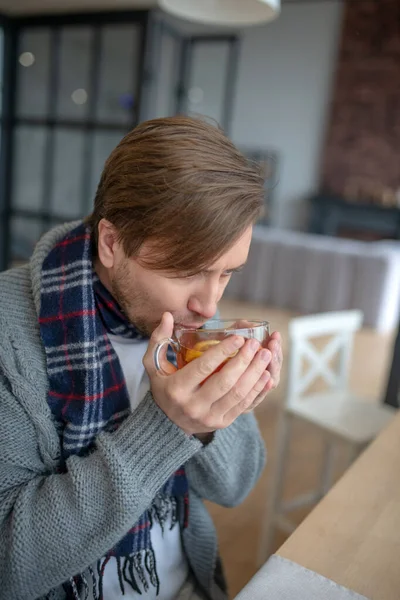 Man wearing warm cardigan and scarf drinking hot tea — Stock Photo, Image