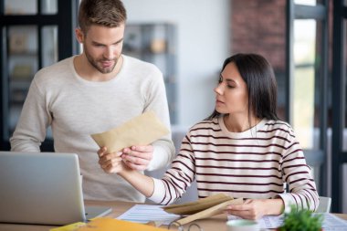 Koyu saçlı bir kadın kocasına mektup yolluyor.