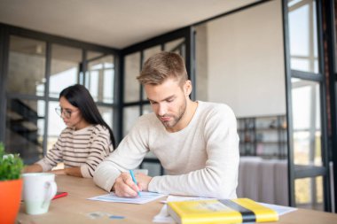 Vergi belgelerini doldururken elinde kalem tutan yakışıklı adam
