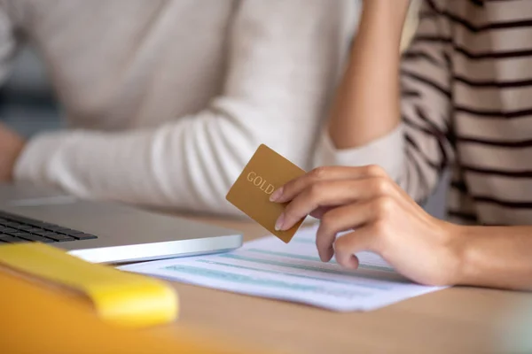 Esposa sosteniendo su tarjeta bancaria de oro mientras hace compras en línea — Foto de Stock