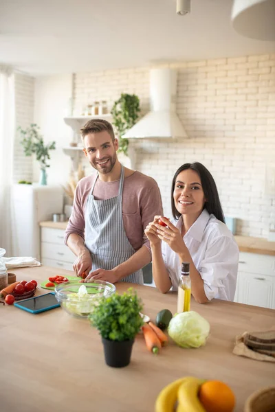 Pareja sintiéndose alegre mientras cocinan el desayuno juntos — Foto de Stock