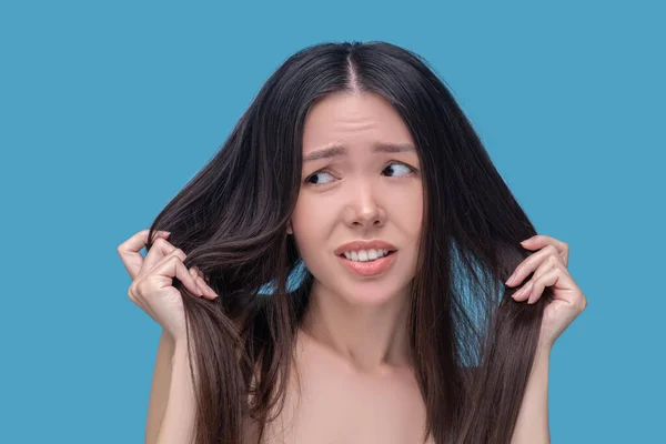 Brunette jeune femme asiatique tenant ses cheveux et se sentant stressée — Photo