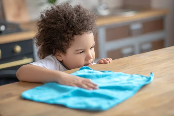 Small cute curly-haired mulatta wiping the table surface — Stock Photo, Image