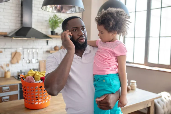 Dark-skinned tall father holding his kid and talking on the phone — Stock Photo, Image