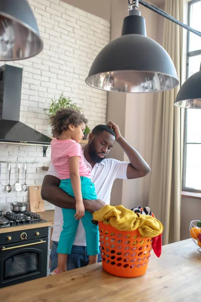 African american man holding his daughter and feeling uncertain — Stock Photo, Image