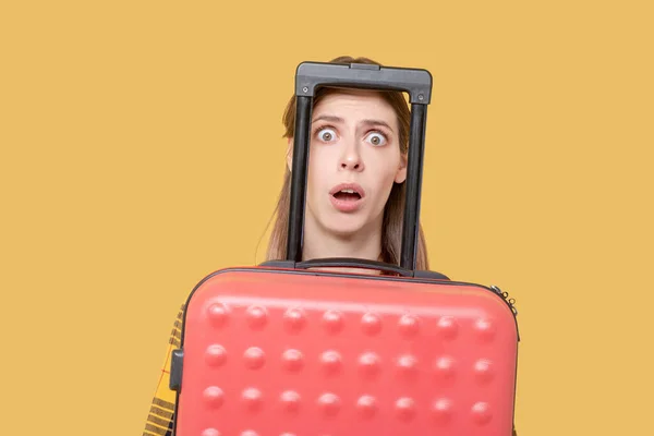Испуганная девушка выглядывает из-за красного чемодана . — стоковое фото