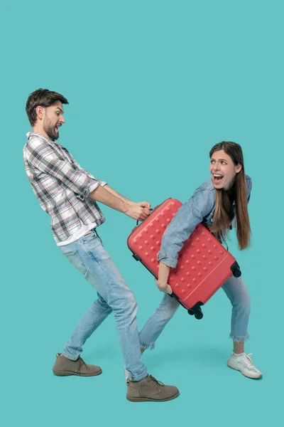 Homem e menina levando uns aos outros mala — Fotografia de Stock