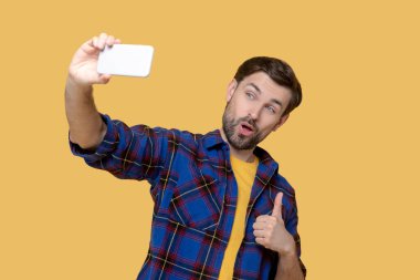 Genç yakışıklı adam akıllı telefondan selfie çekiyor.