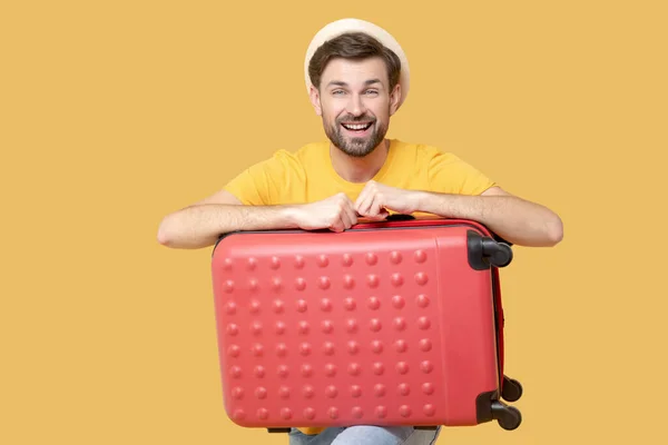 Smiling young adult man with a red suitcase — Stock Photo, Image