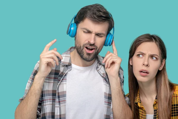 Hombre en auriculares con los ojos cerrados y una chica seria — Foto de Stock