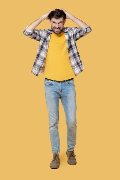 Uomo in camicia a quadri e jeans che cammina, mani vicino alla testa — Foto Stock