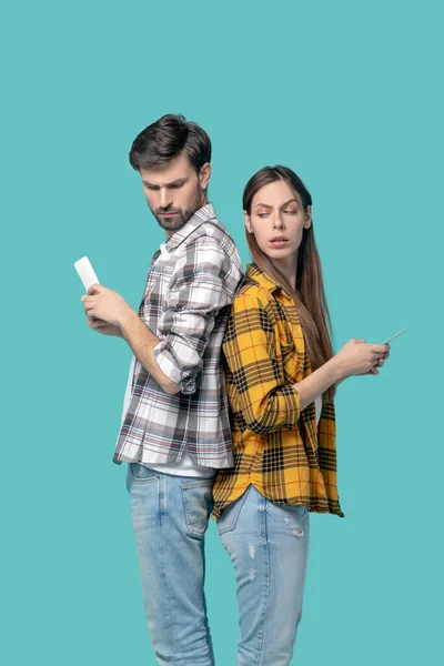 Homem e menina em camisas quadriculadas com smartphones . — Fotografia de Stock