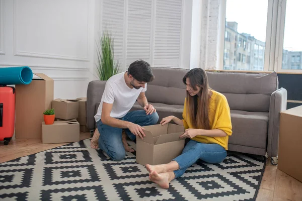 Мужчина и девушка сидят на полу рядом с картонной коробкой . — стоковое фото