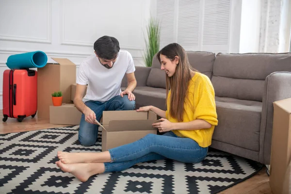 Long-haired girl and bearded man folding things into box