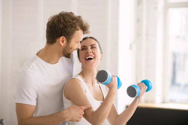 Mujer sonriente teniendo un entrenamiento con pesas junto con su marido y buscando disfrutado — Foto de Stock