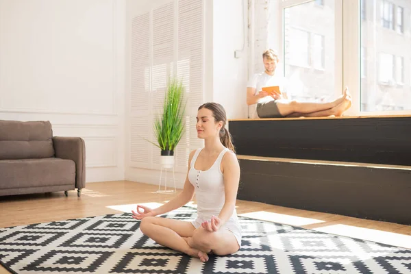 Young woman in white sportswear meditating and smiling — Stock Photo, Image