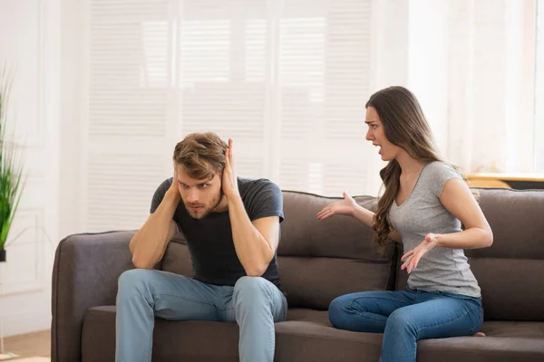Langharige jonge vrouw schreeuwen naar haar man terwijl hij sluit zijn oren — Stockfoto