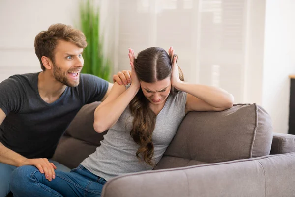 Молодий бородатий чоловік кричить на свою дружину, коли вона закриває вуха — стокове фото