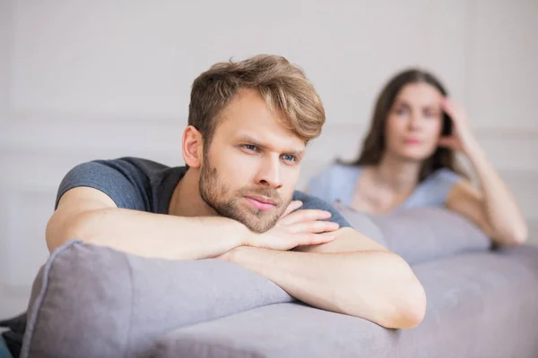 Młody brodaty mężczyzna siedzący z depresyjnym spojrzeniem po kłótni z żoną — Zdjęcie stockowe