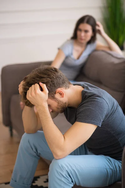 Jovem casal sentado no sofá depois de uma briga e olhando infeliz — Fotografia de Stock