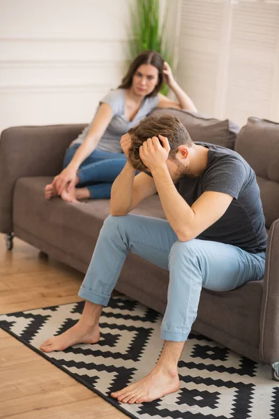 Fiatal pár ül a kanapén veszekedés után, és depressziósnak tűnnek. — Stock Fotó