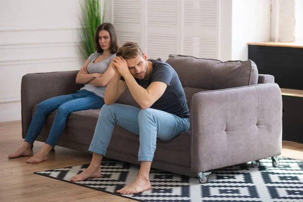 Молода пара сидить на дивані після сварки і виглядає засмученою — стокове фото