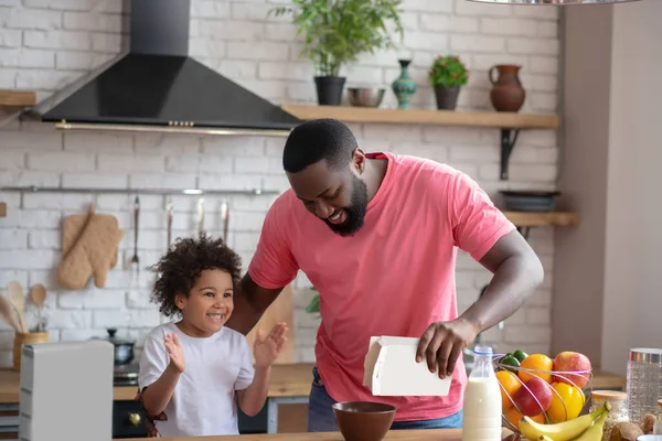 Africano americano barbudo hombre verter maíz copos en su hijas plato — Foto de Stock